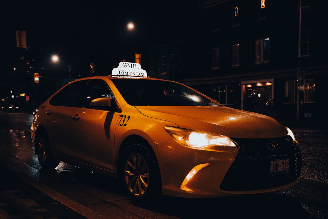 why-choose-us A yellow taxi waiting at night in London, Ontario, Canada. Urban transportation captured with street lights.