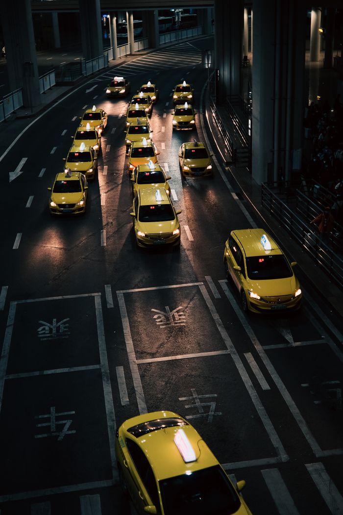 services-01 High angle view of lined yellow taxis on urban street during nighttime.