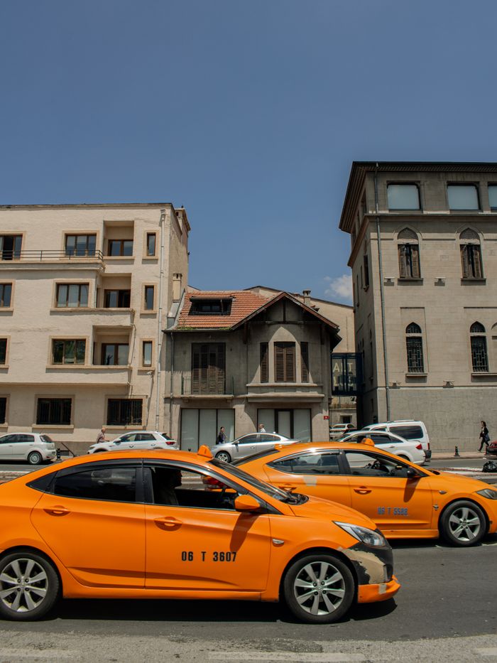 gallery-3 Street view of yellow taxis in front of historic buildings under clear blue sky.