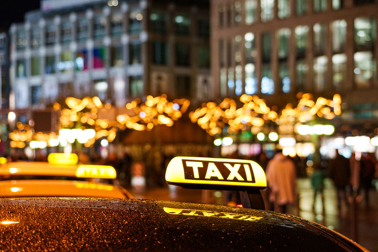 our-experience Glistening taxis at night with festive city lights, creating a vibrant urban atmosphere.