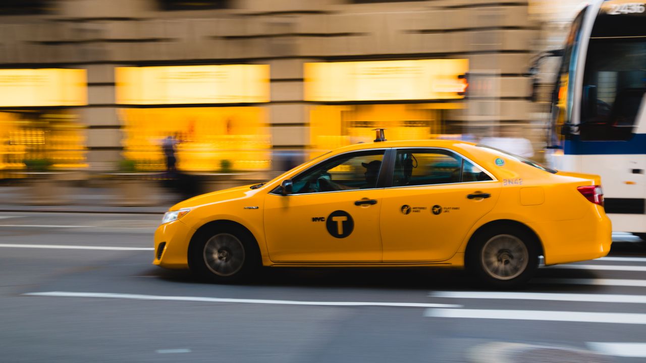 services-03 A New York City yellow taxi speeds through urban streets, capturing the bustle of city life.