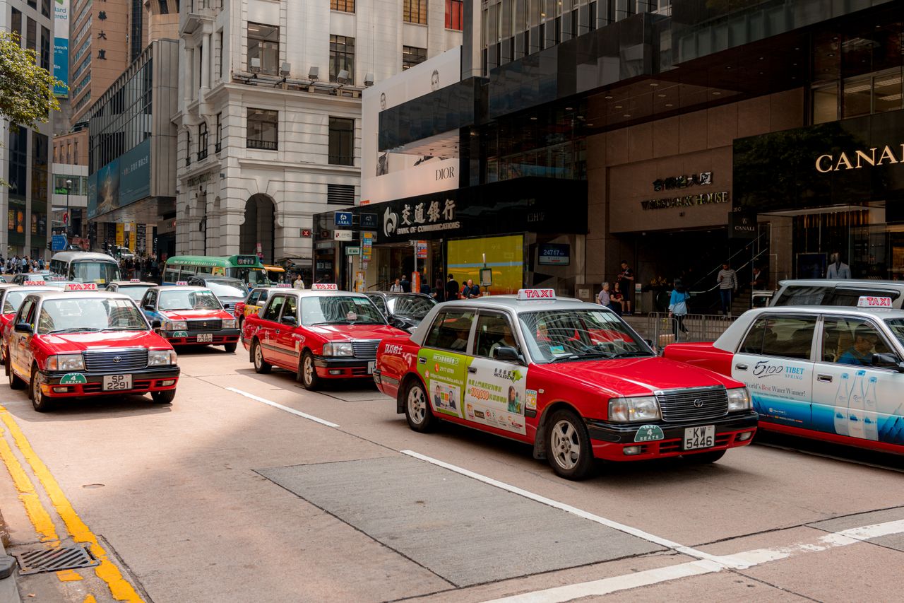 gallery-1 Bustling city street with red taxis and busy shops in downtown on a sunny day.